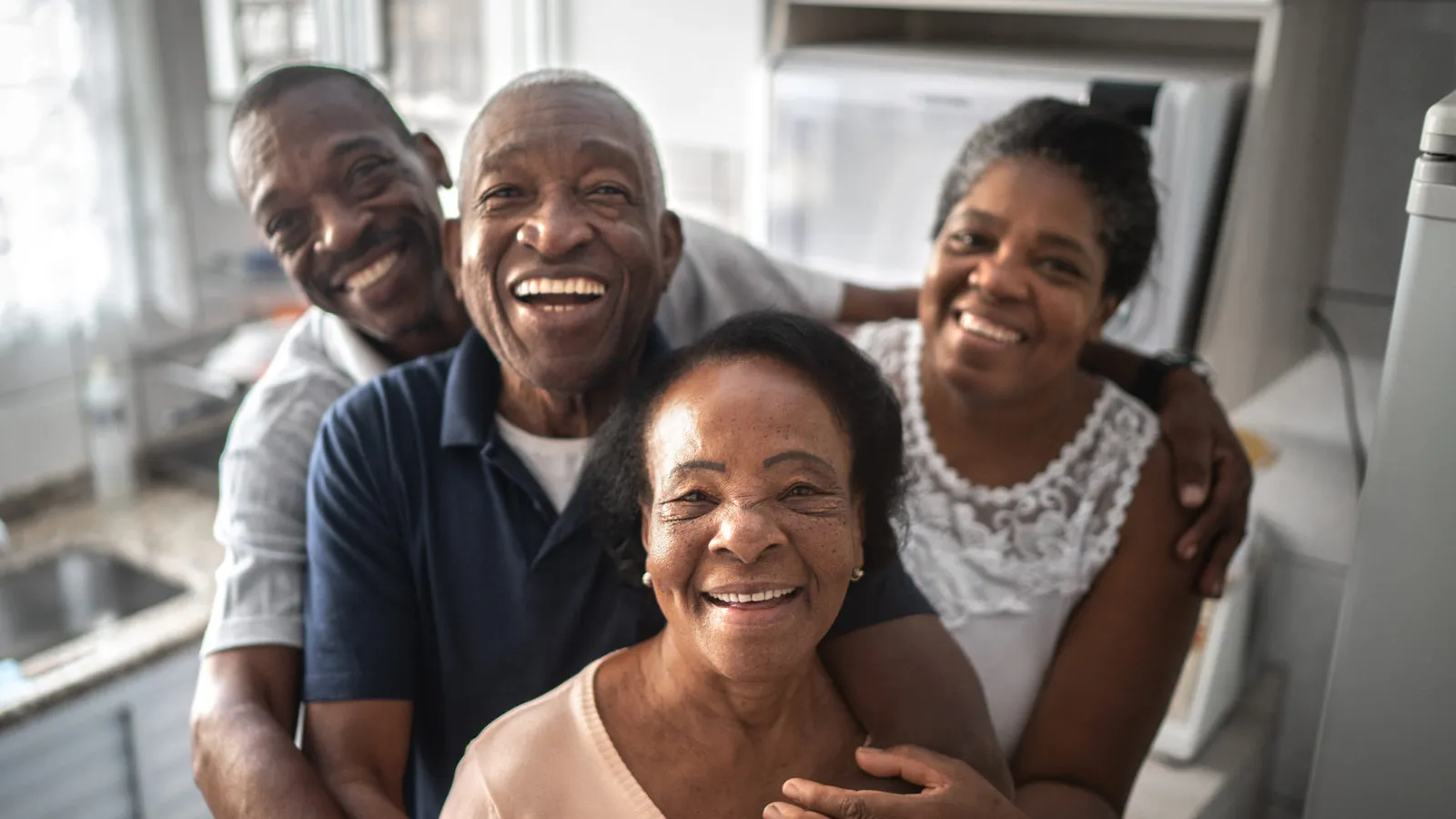 Several generations of a family smiling together in a kitchen