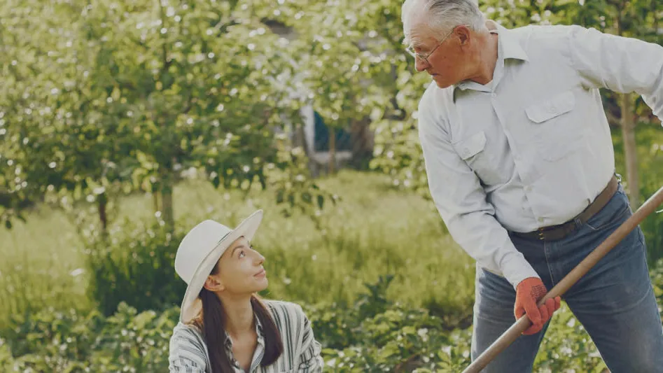 An older man gardening while a woman looks on