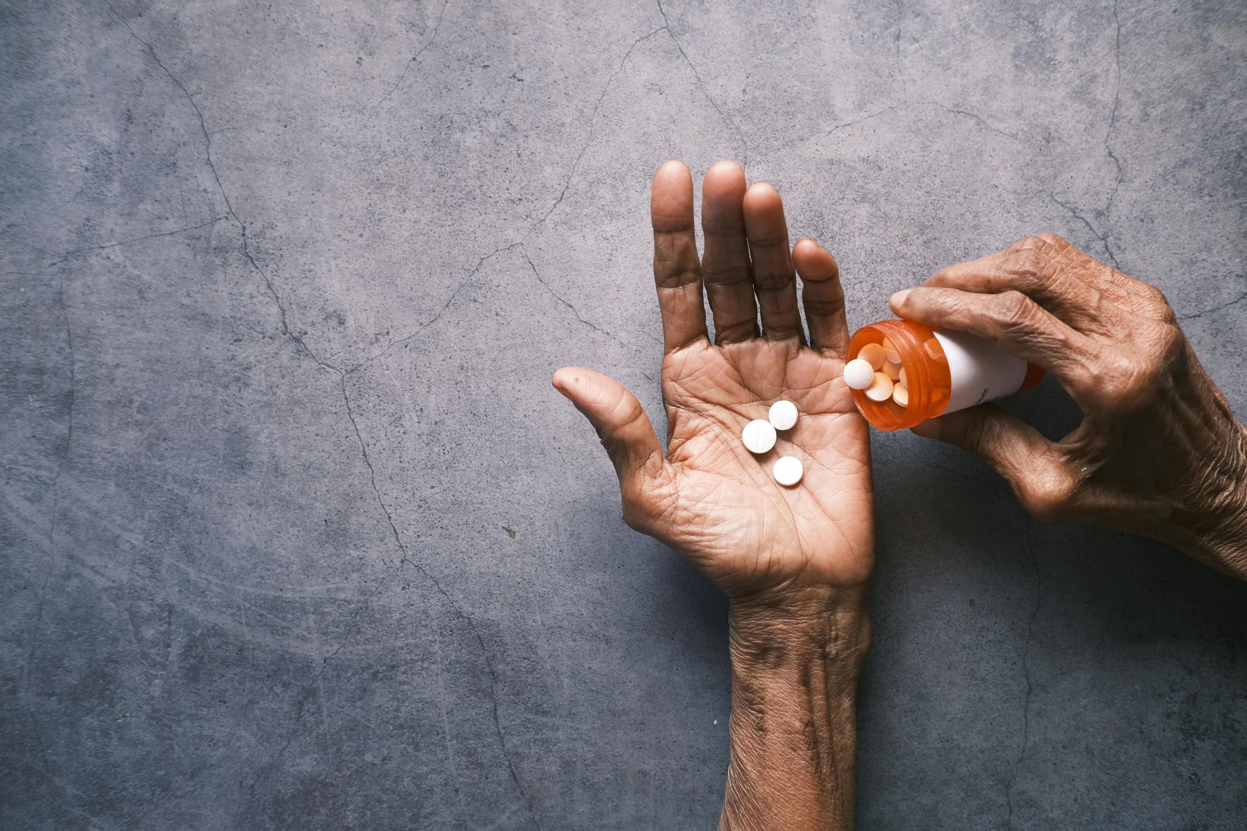 An older hand holding medication