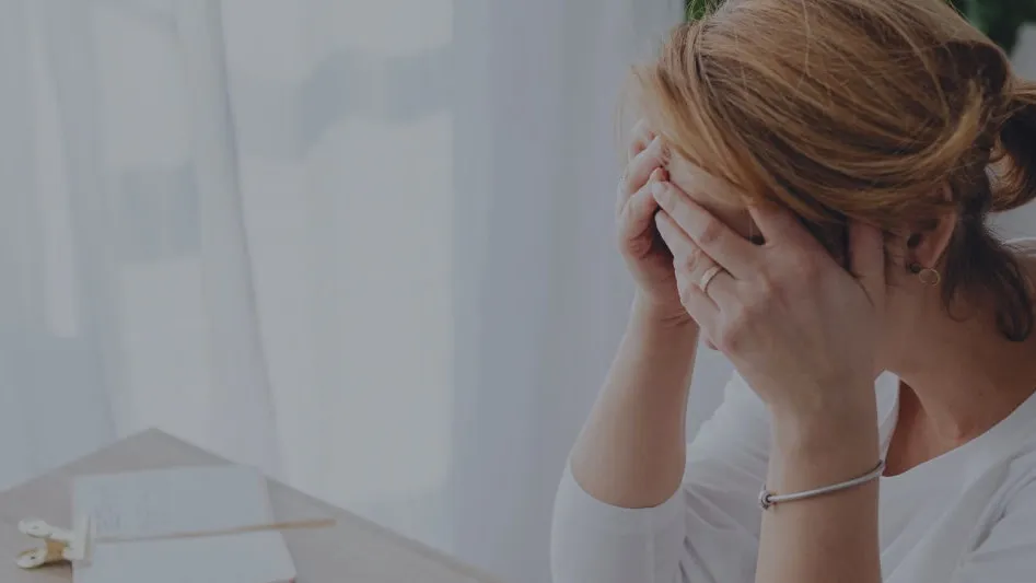 A woman at a desk with her hands over her face
