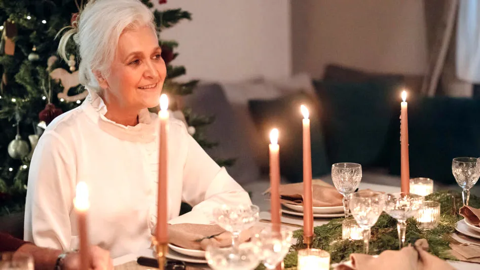 An older woman at a candlelit holiday dinner table
