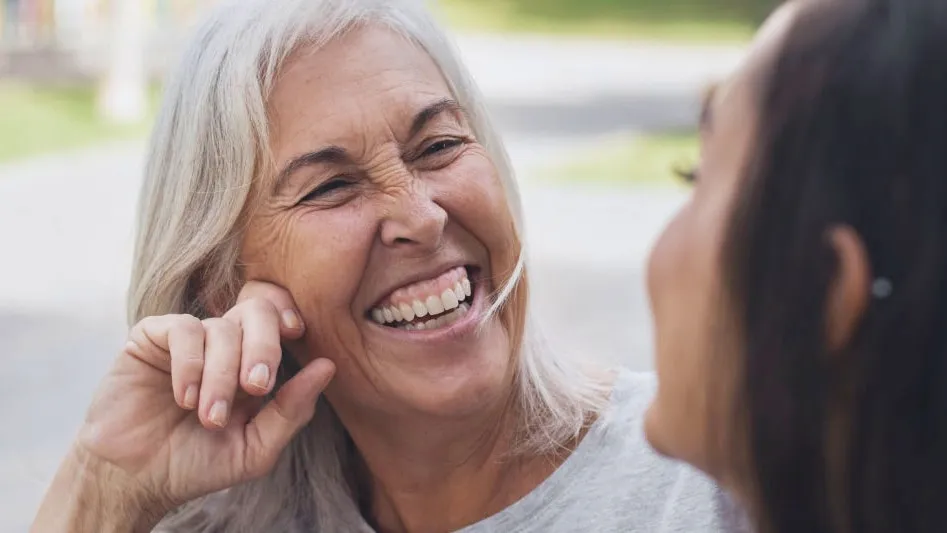 An older woman laughing with a younger woman outdoors