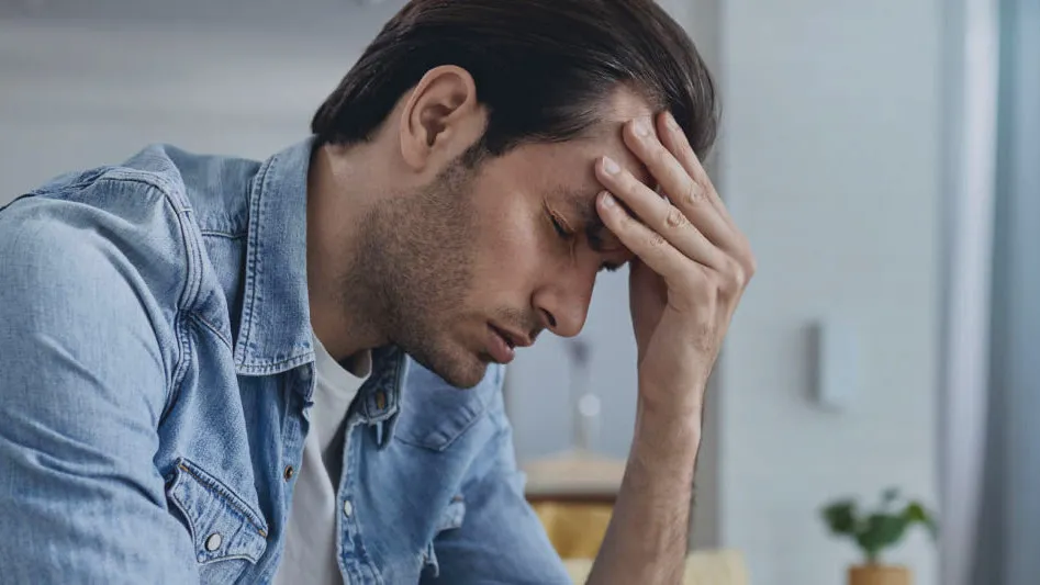 A man sitting at a desk with his head in his hand