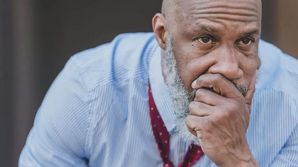 A man wearing a work lanyard resting his chin on his hand