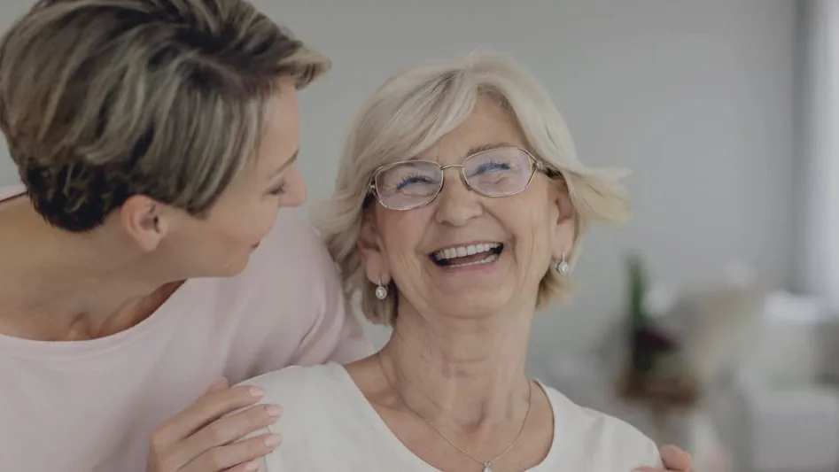 An older woman laughing with her adult daughter
