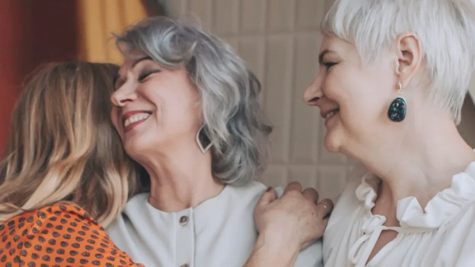 Three women laughing together in a close embrace