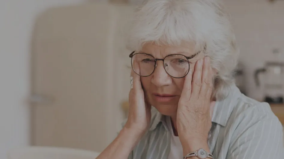 An older woman looking worried with her hands to her head